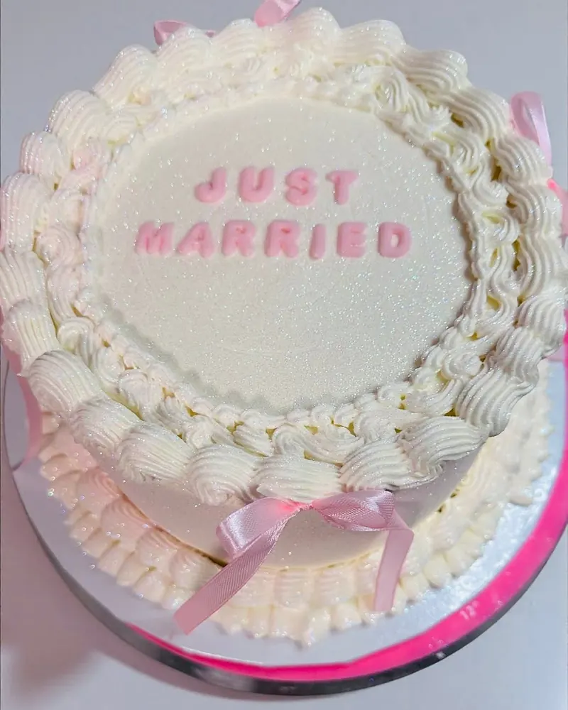 עוגת חתונה לבנה עם כיתוב Just Married וסרט ורוד
